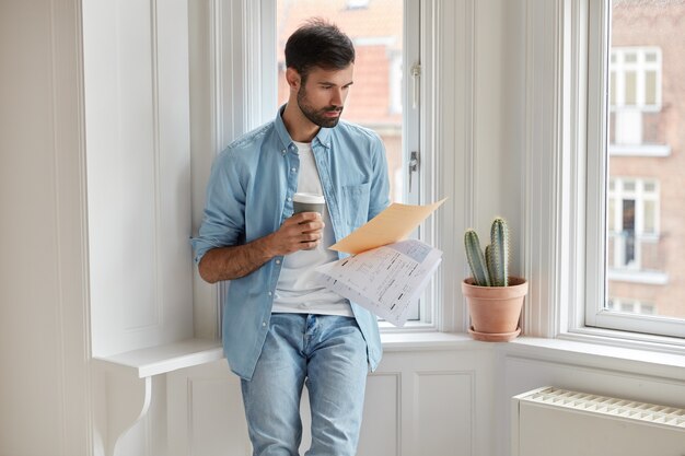 Serious businessman reads text of contract, analyzes documentation, concentrated on financial information