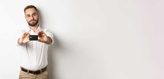 Serious businessman showing credit card standing over white background