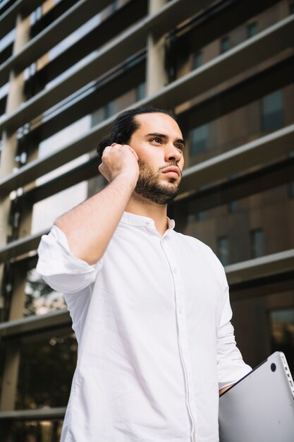 Серьезный бизнесмен, стоя перед зданием говорить по Bluetooth