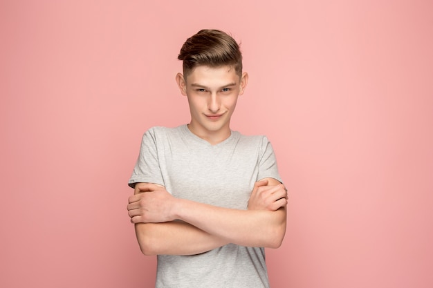 The serious businessman standing and looking at camera against pink background.