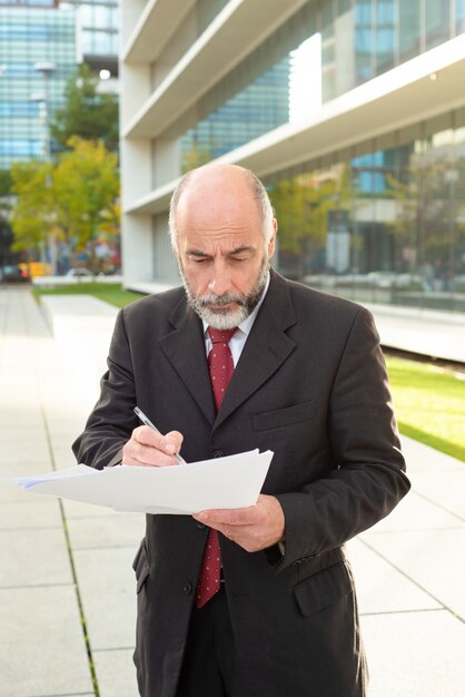 Serious businessman taking notes on street