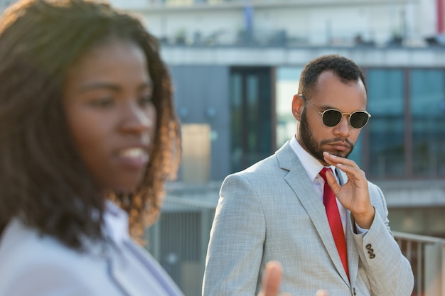 Serious businessman walking outside by his female colleague