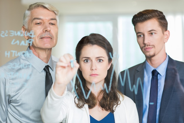 Free photo serious businesswoman drawing graph on glass screen