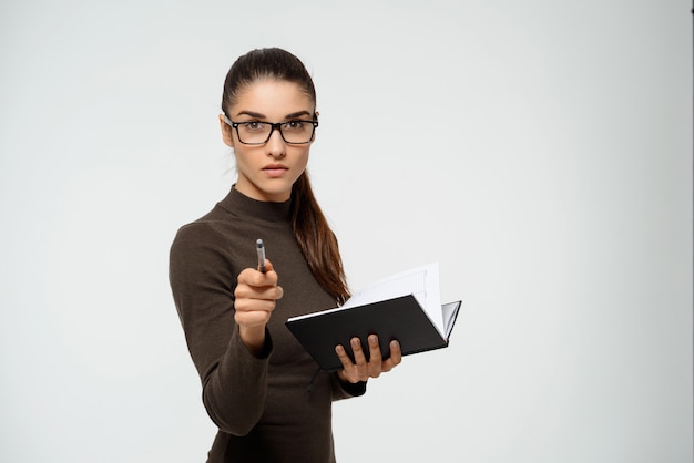 Serious businesswoman pointing at you, hold notebook