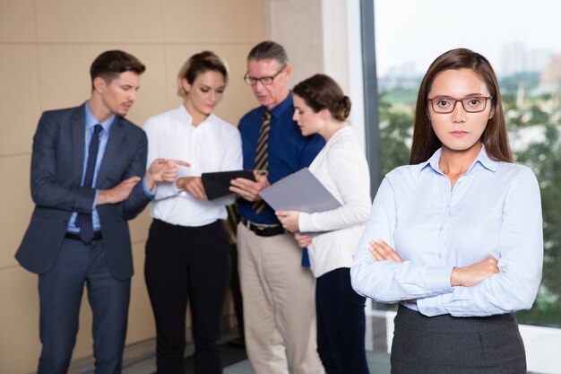 Serious Businesswoman Standing in Front of Team