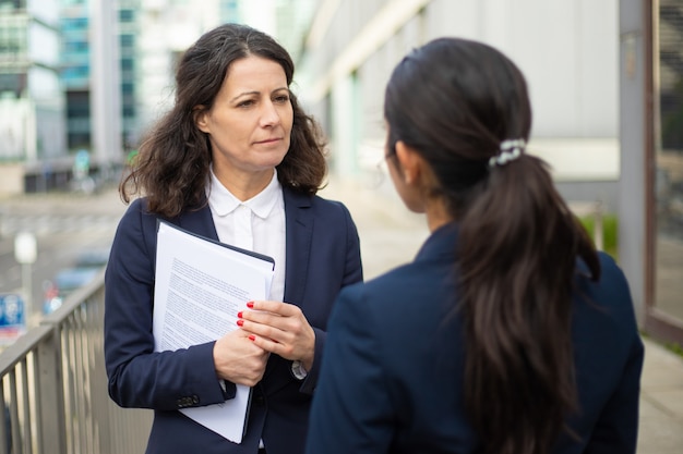 Serious businesswomen talking on street