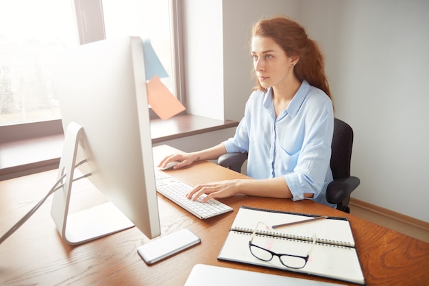 Foto gratuita impiegato di ufficio femminile occupato serio, tastiera sul computer