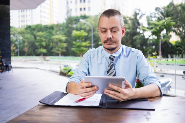 Serious busy freelancer watching video on tablet