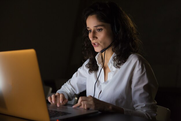 Serious call center worker with headset and laptop