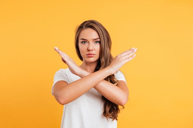 Serious caucasian woman standing near copyspace showing stop gesture.