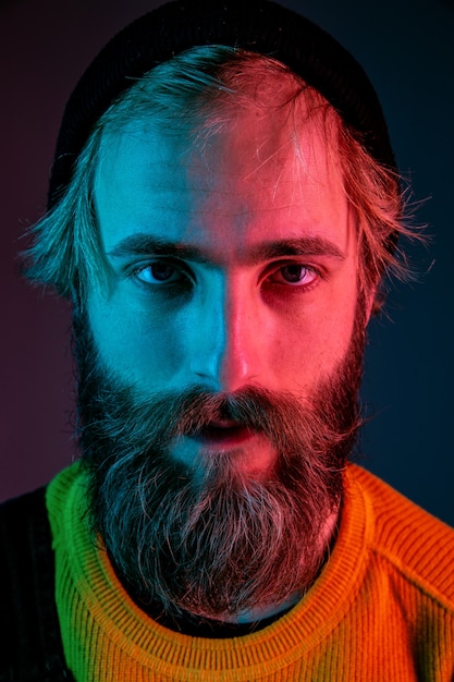 Serious, close up. Caucasian man's portrait on gradient  space in neon light