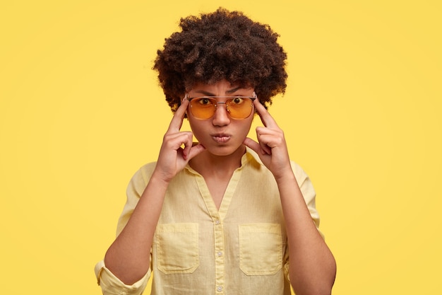 Free photo serious concentrated woman student keeps fingers on temples, tries to ease tension