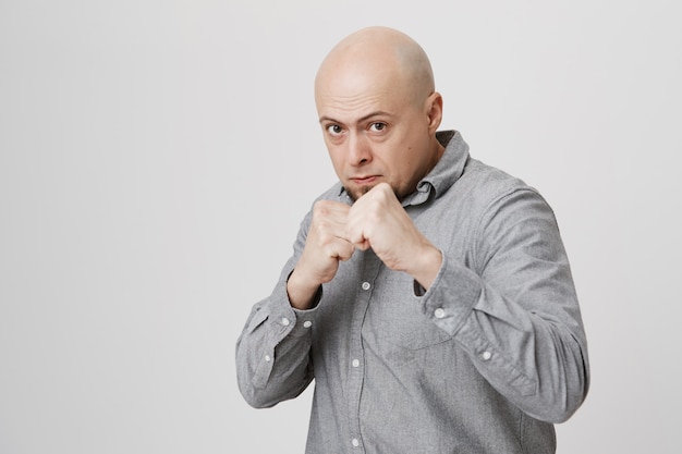 Serious confident bald man fighting, clench fists