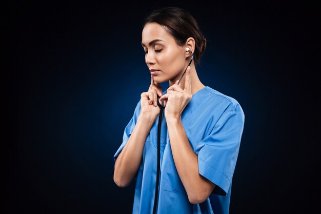 Serious confident lady listening stethoscope isolated