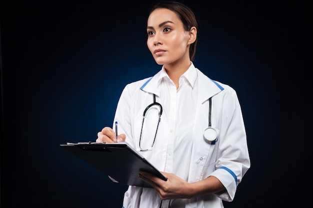 Serious confident lady with clipboard looking aside