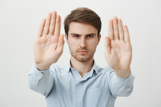 Free photo serious confident man extend hands to shop stop, warning or restriction