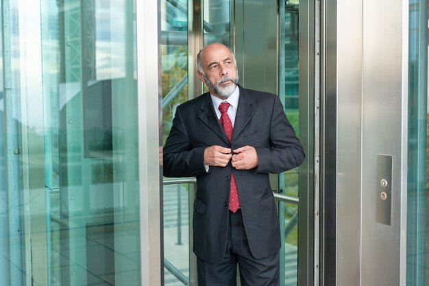 Serious confident mature businessman using office elevator