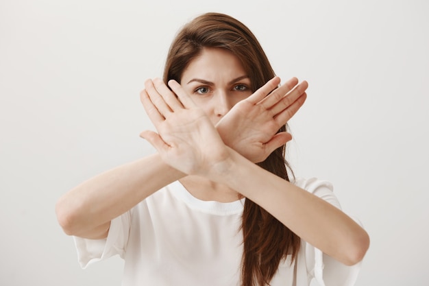 Serious confident woman make cross gesture to refuse or stop someone