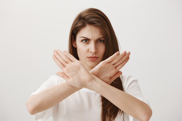 Serious confident woman make cross gesture to refuse or stop someone