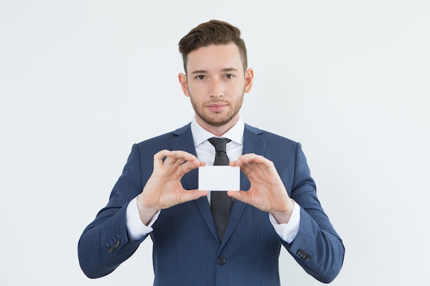 Free photo serious confident young businessman showing card