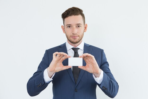 Serious confident young businessman showing card