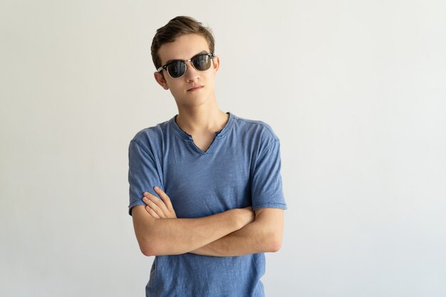 Serious confident young man in sunglasses crossing arms on chest