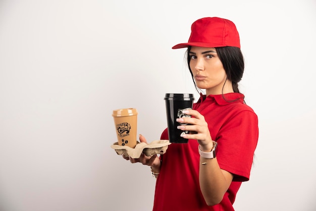 Serious courier posing with two cups of coffee on white background. High quality photo