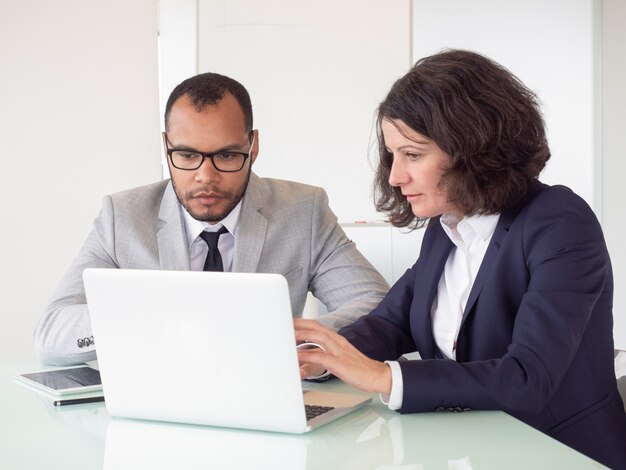 Serious coworkers using laptop