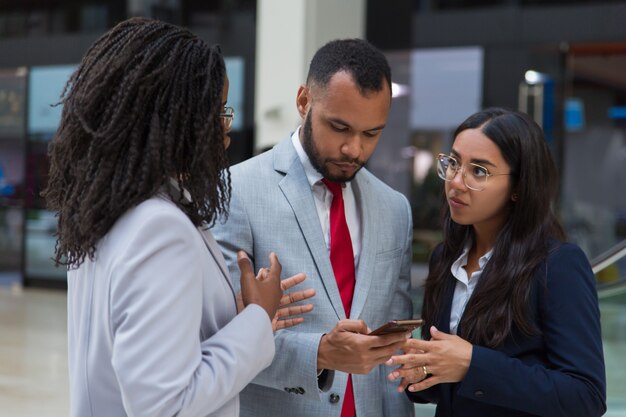 Serious coworkers using smartphone