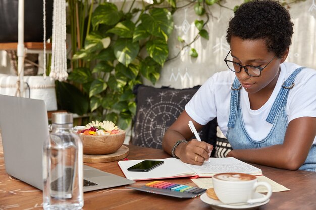 Serious dark skinned female college student makes research