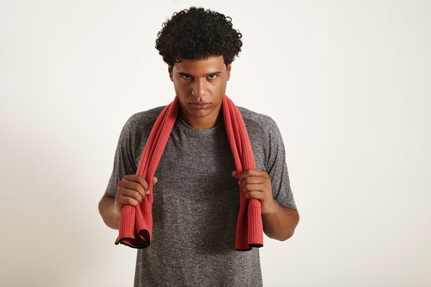 Serious determined African American athlete wearing gray shirt grabbing red towel over his neck