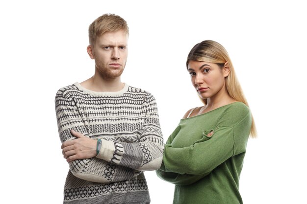 serious dissatisfied European young wife and husband keeping arms folded and frowning while having argument, not going to make concessions about making important decision