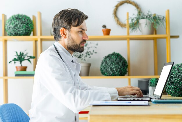 Serious doctor using laptop in office