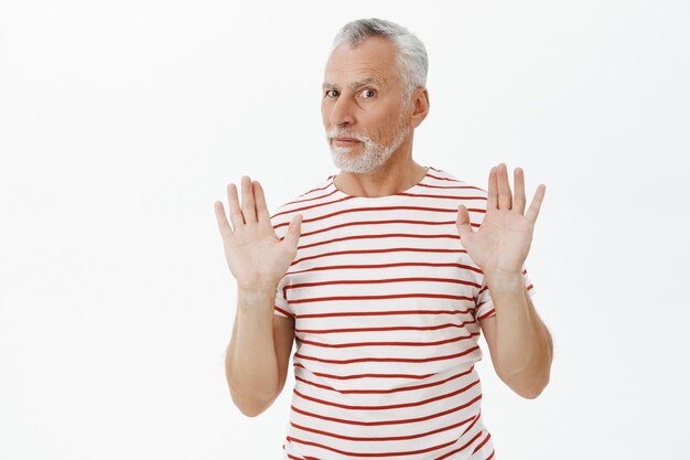 Serious elderly man prohibit something, raising hands in stop, rejection gesture