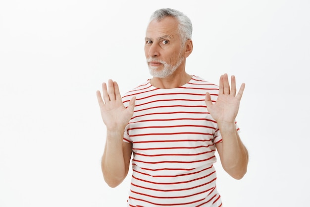 Serious elderly man prohibit something, raising hands in stop, rejection gesture