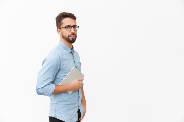 Serious entrepreneur in eyeglasses with tablet looking