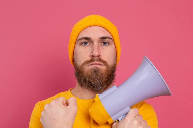 Serious european man with megaphone on pink background