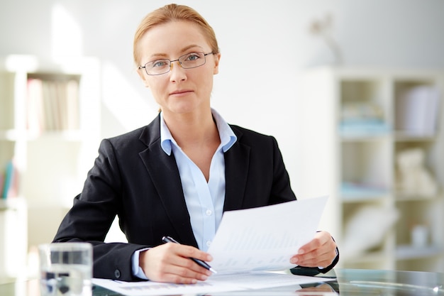 Serious executive holding a pen and a report