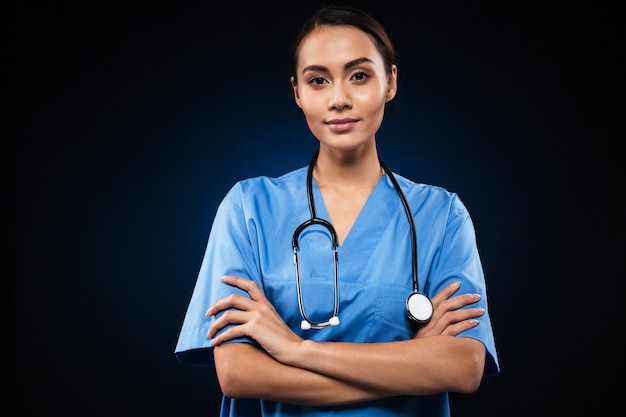 Serious female doctor looking and holding hands folded isolated