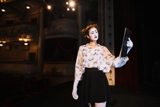 Serious female mime looking at script while rehearsing on stage