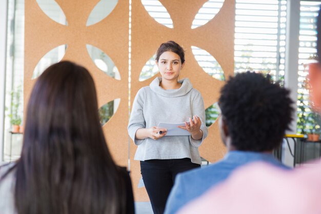 Serious female woman presenting project to classmates
