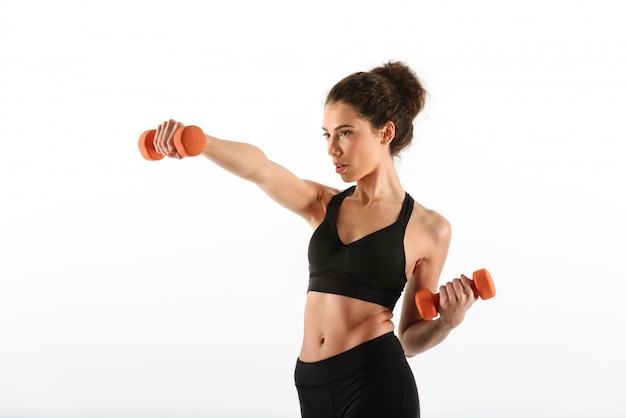 Serious fitness woman doing exercise with dumbbells and looking away