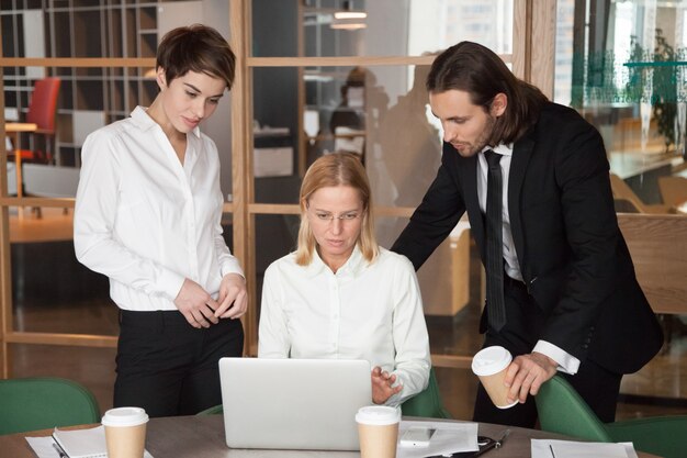 Serious focused business team discussing online task together in office