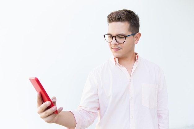 Serious focused guy in eyeglasses reading message