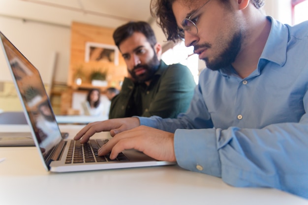 Uomo messo a fuoco serio che utilizza computer portatile nell'ufficio