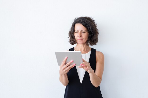 Serious focused woman in casual using tablet