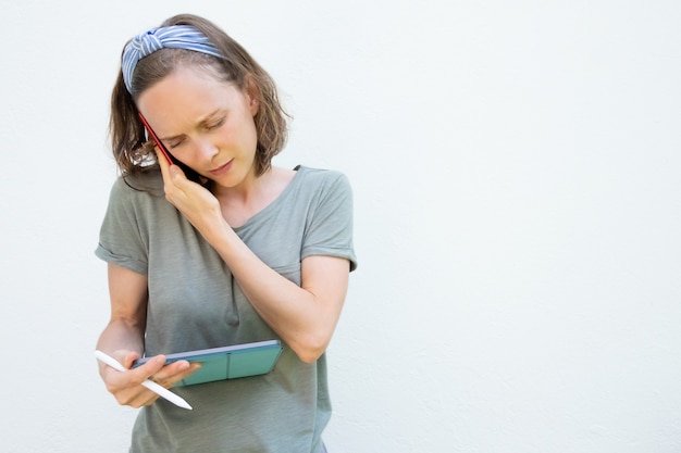 Serious focused young woman using tablet and pen