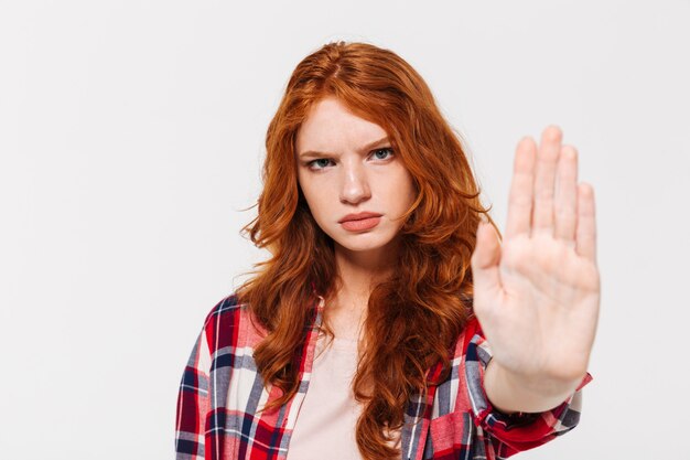 serious ginger woman in shirt showing stop gesture