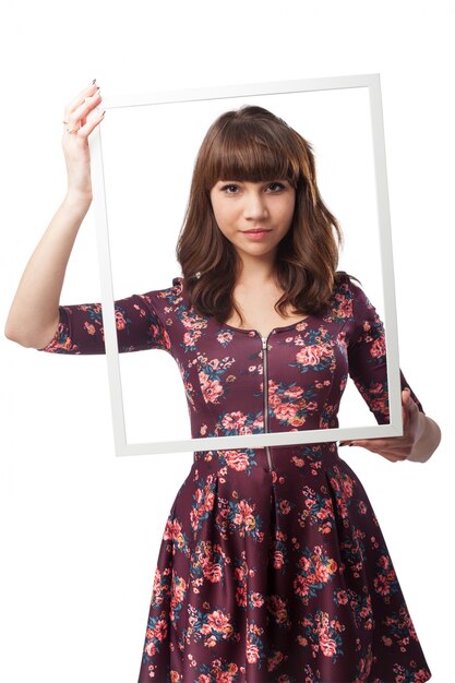 Serious girl holding a frame in front of her