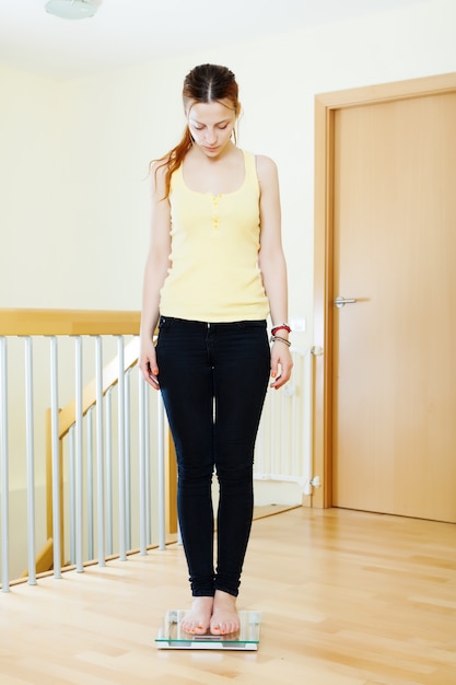 serious girl standing on bathroom scales